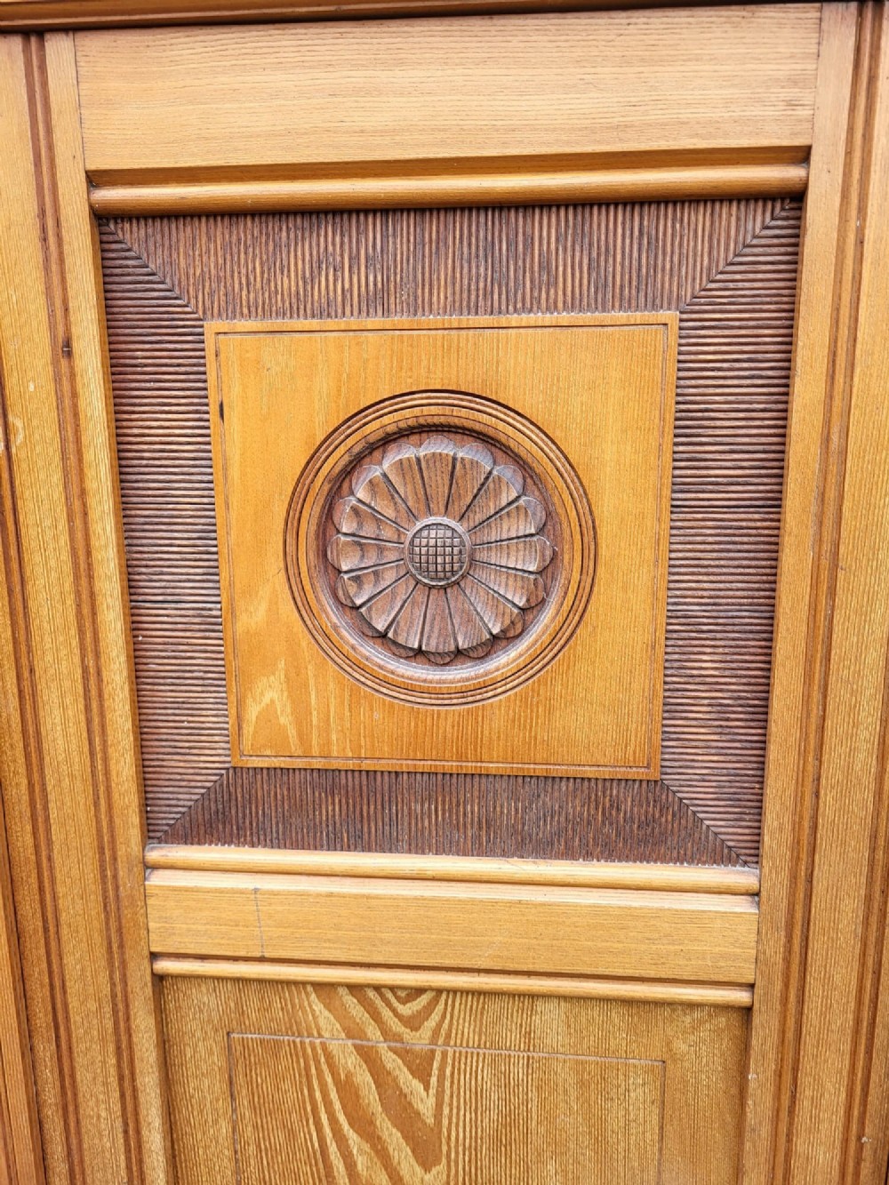 An Edwardian Arts and Crafts oak and ash bedroom suite comprising a mirror-door wardrobe with inlaid panels and a matching pedestal dressing table. View V