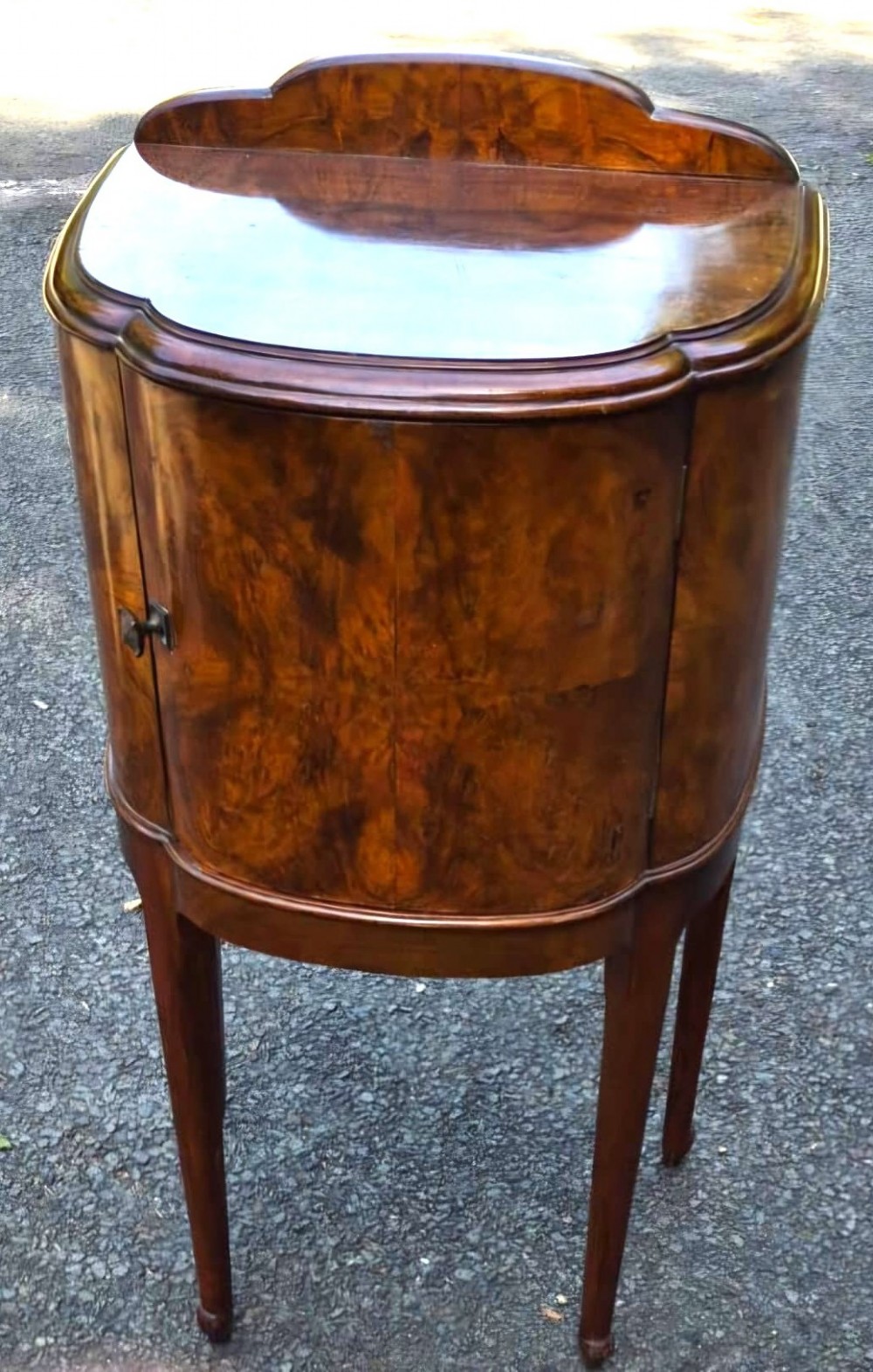 A seven-piece Art Deco bedroom suite crafted in burr walnut with arched tops, featuring a large wardrobe, triple-mirror dressing table, tallboy chest, bedside cupboard, stool, and two chairs. View VII