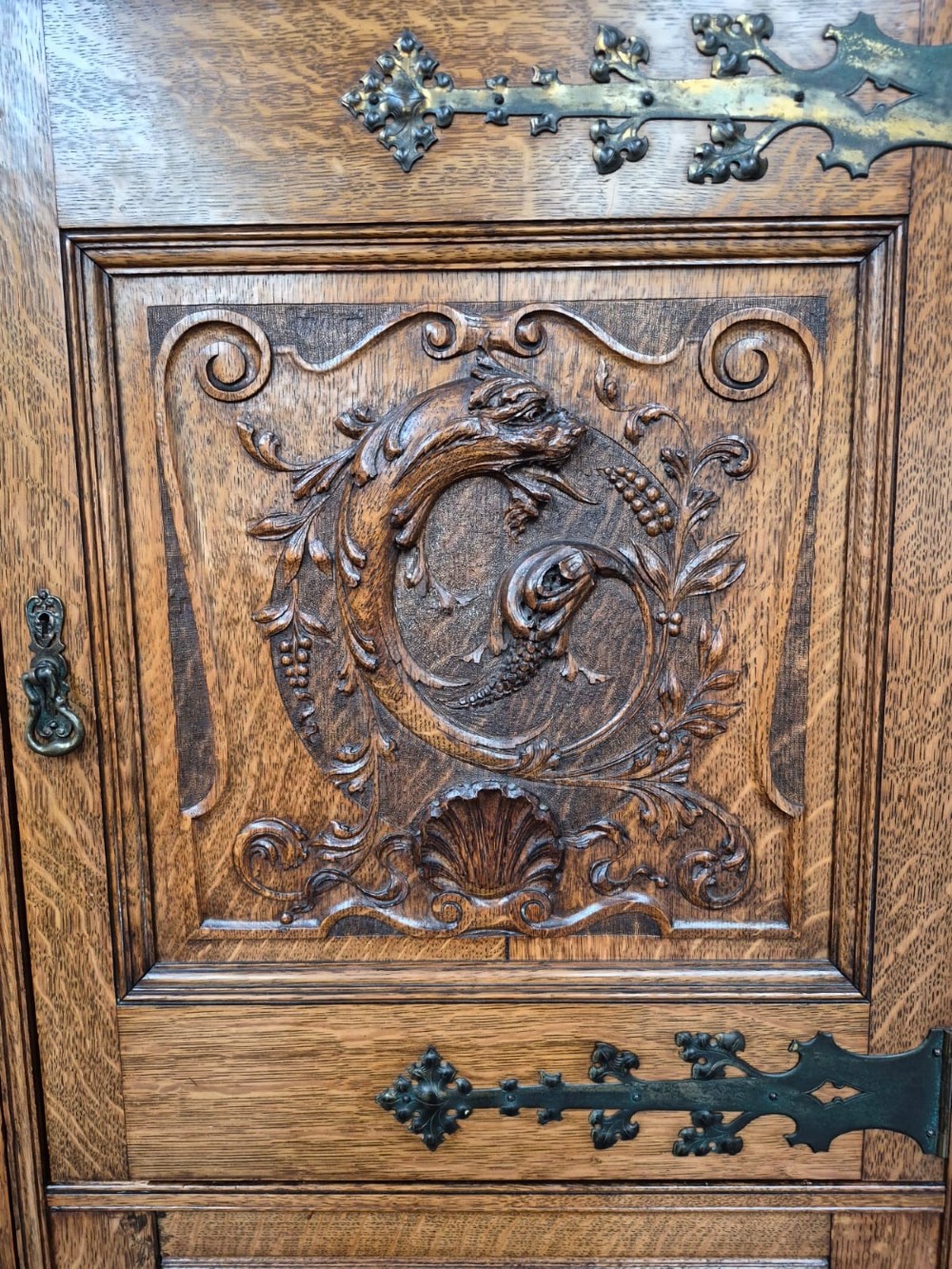 A six-piece golden oak Arts and Crafts bedroom suite including a central compactum wardrobe with mirrors, a dressing chest, a desk, a pot cupboard, and two rush-seat chairs. View IV