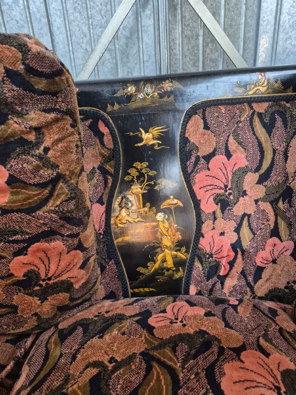 A three-piece Edwardian seating suite comprising a central two-seater settee and two matching armchairs with black lacquered frames adorned with gilded Chinoiserie patterns and pink floral pattern fabric upholstery. View V
