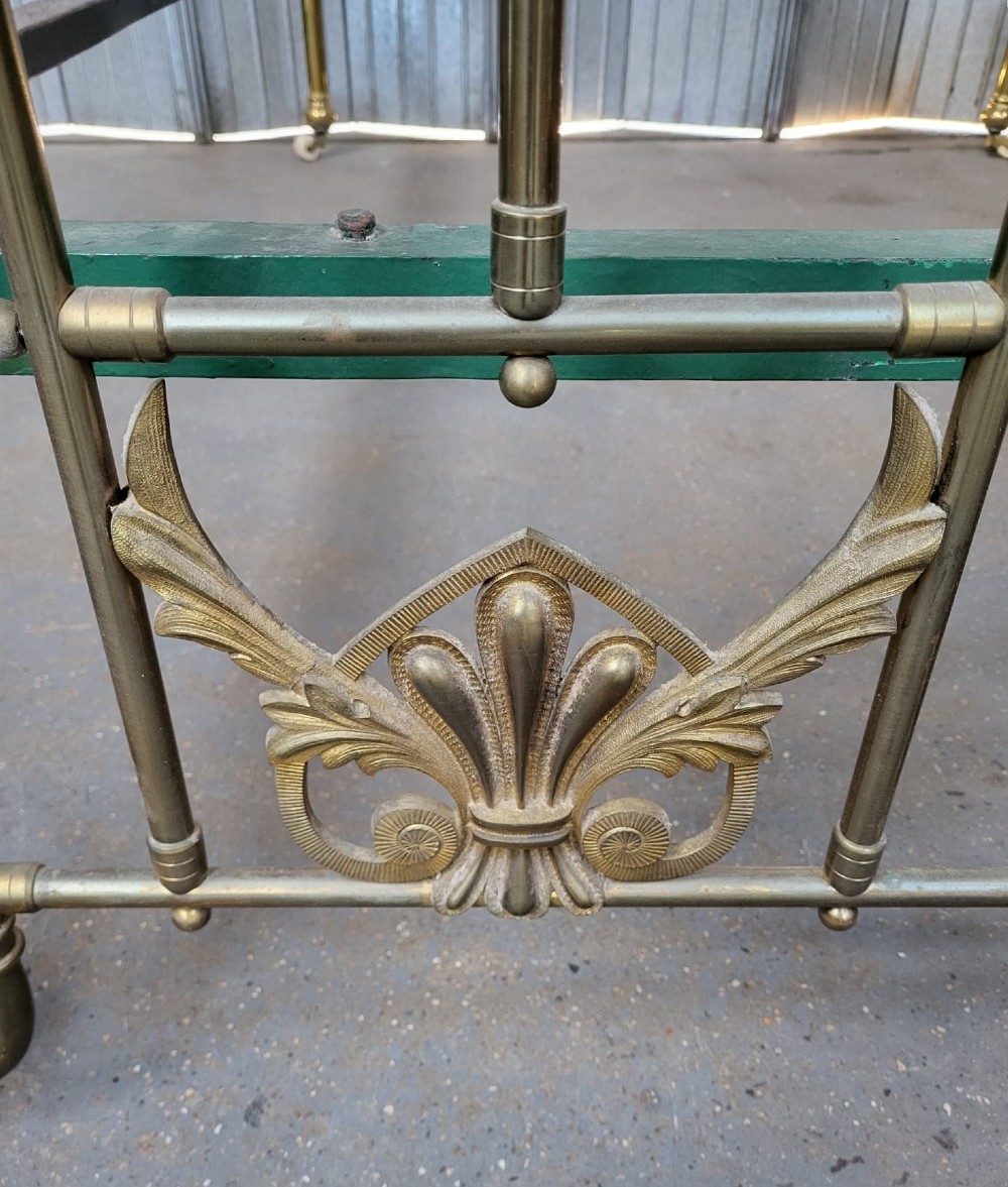 An antique Victorian double bedstead constructed from tubular brass featuring ornate cast foliate motifs, vertical metal spindles, ball finials, and original castors. View III