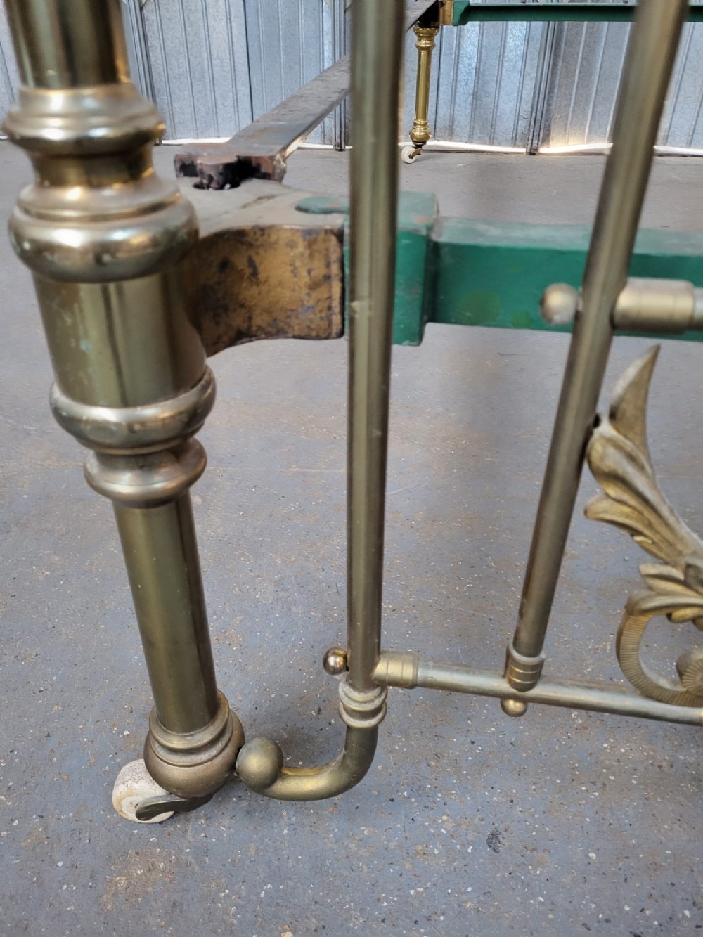 An antique Victorian double bedstead constructed from tubular brass featuring ornate cast foliate motifs, vertical metal spindles, ball finials, and original castors. View IV