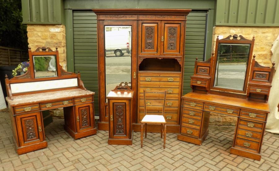 A multi-piece Victorian bedroom suite crafted from carved burr walnut, featuring a compactum wardrobe with mirror, a dressing table with drawers, a marble-top washstand, a pot cupboard, and a side chair.