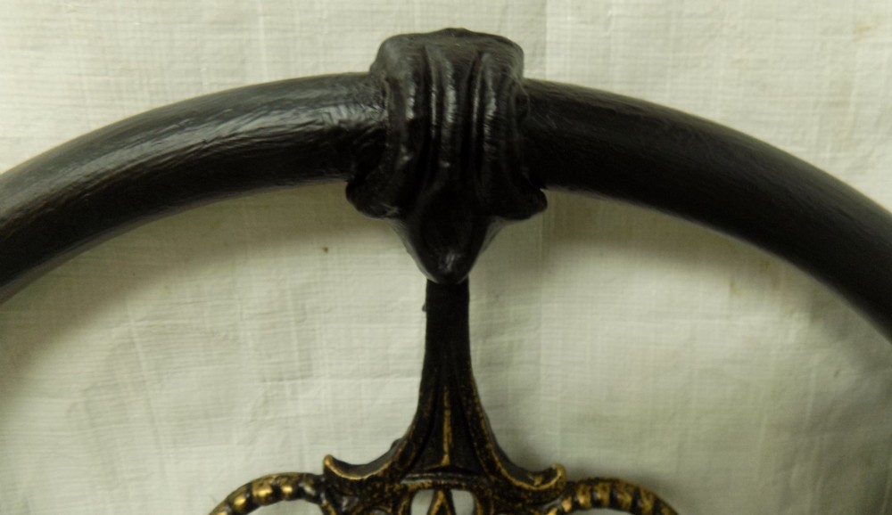 A Victorian double iron bedstead featuring a black tubular frame with arched top rails and central circular medallions with gold filigree detail. View VII