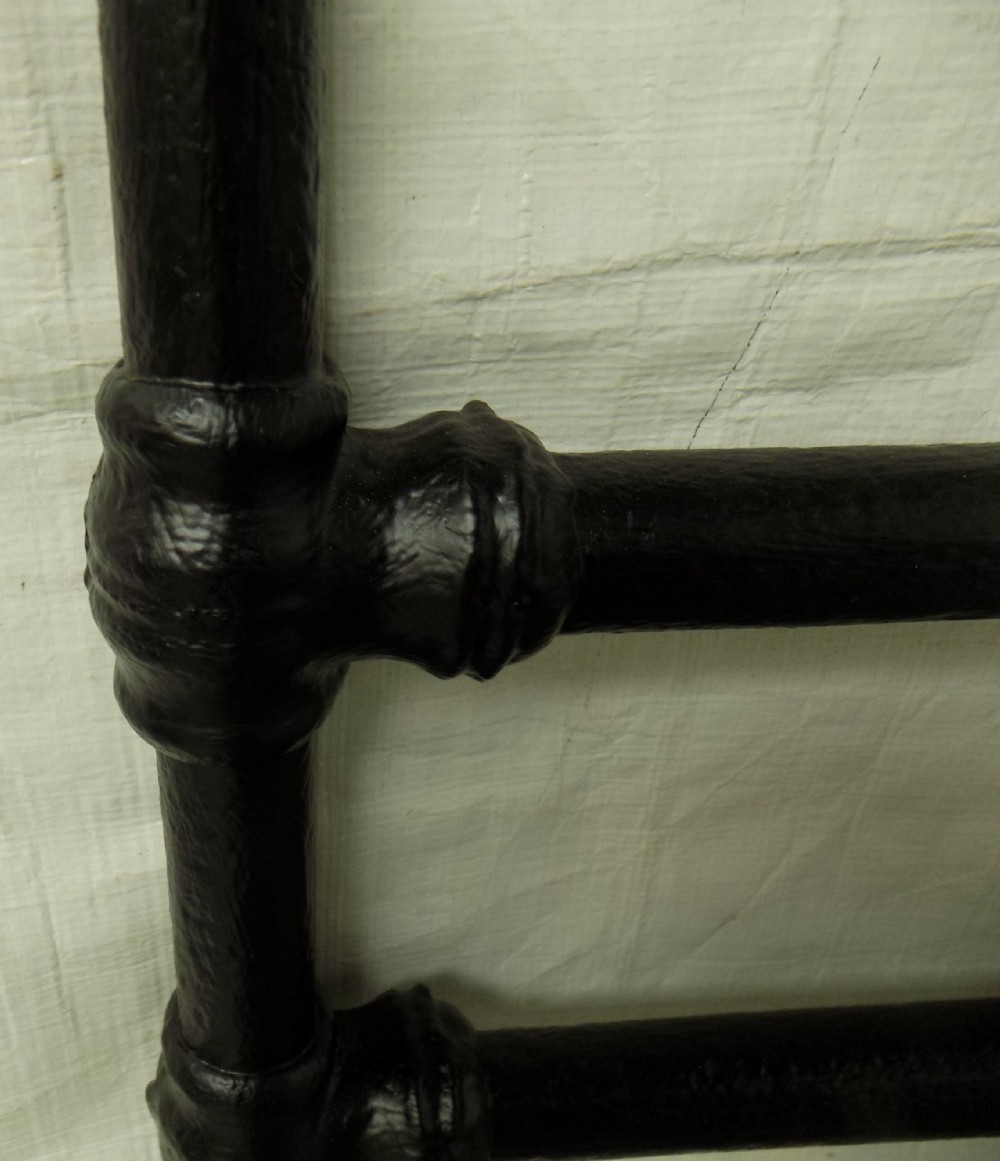 A Victorian double iron bedstead featuring a black tubular frame with arched top rails and central circular medallions with gold filigree detail. View IX
