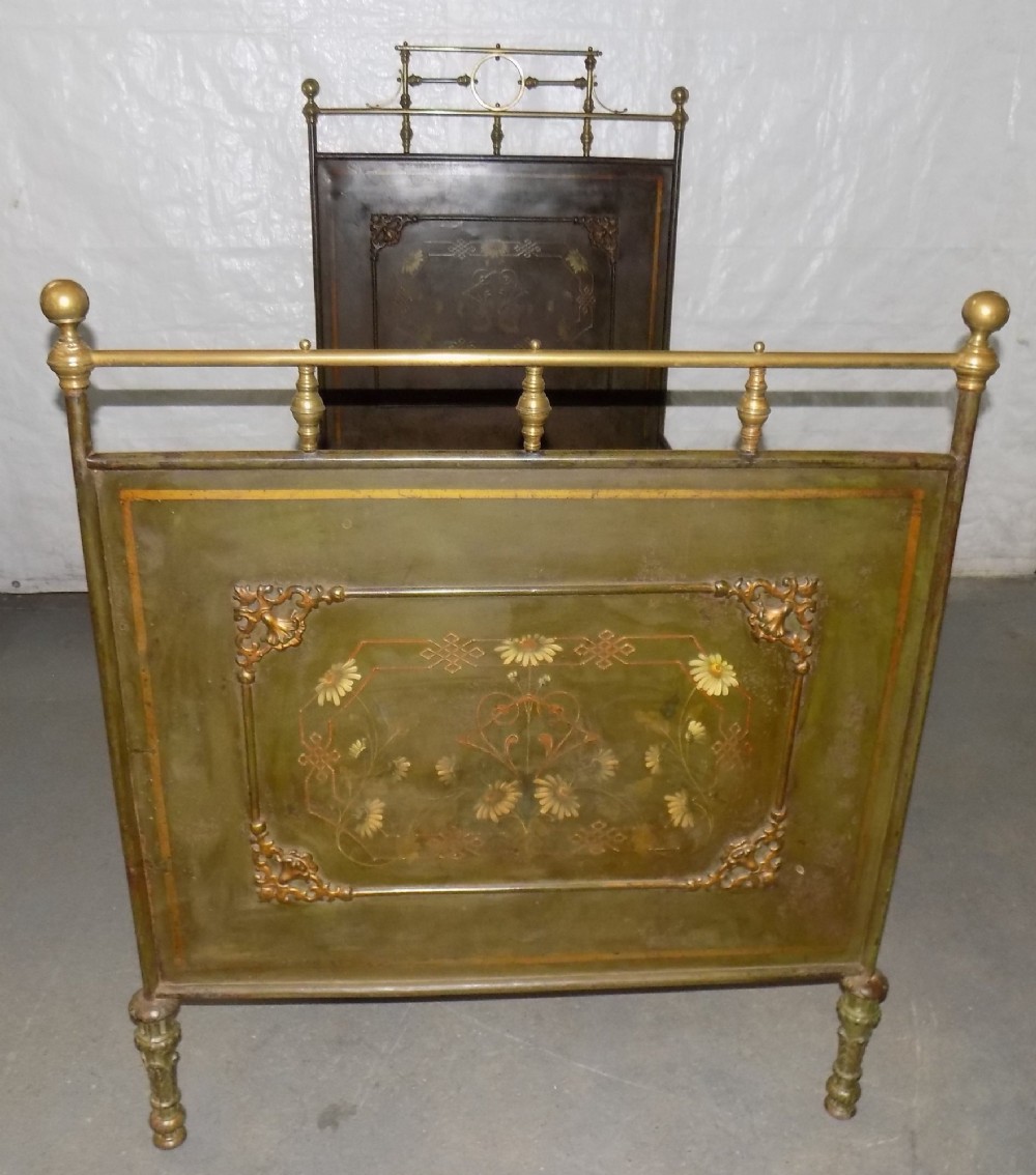 An Austrian 19th-century single toleware bedstead featuring green painted panels with floral motifs, brass top rails, and spherical finials.