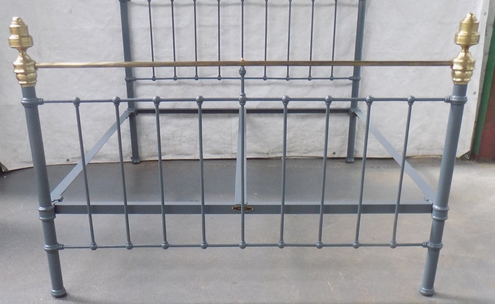 A Victorian grey painted iron bedstead featuring vertical spindles, horizontal brass top rails, and decorative brass corner finials. View III