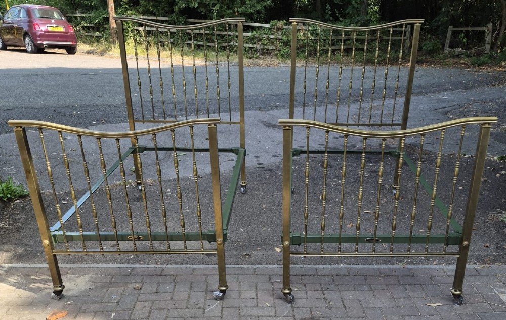 A pair of late Victorian brass single bedsteads featuring vertical spindles with turned detailing and curved top rails.