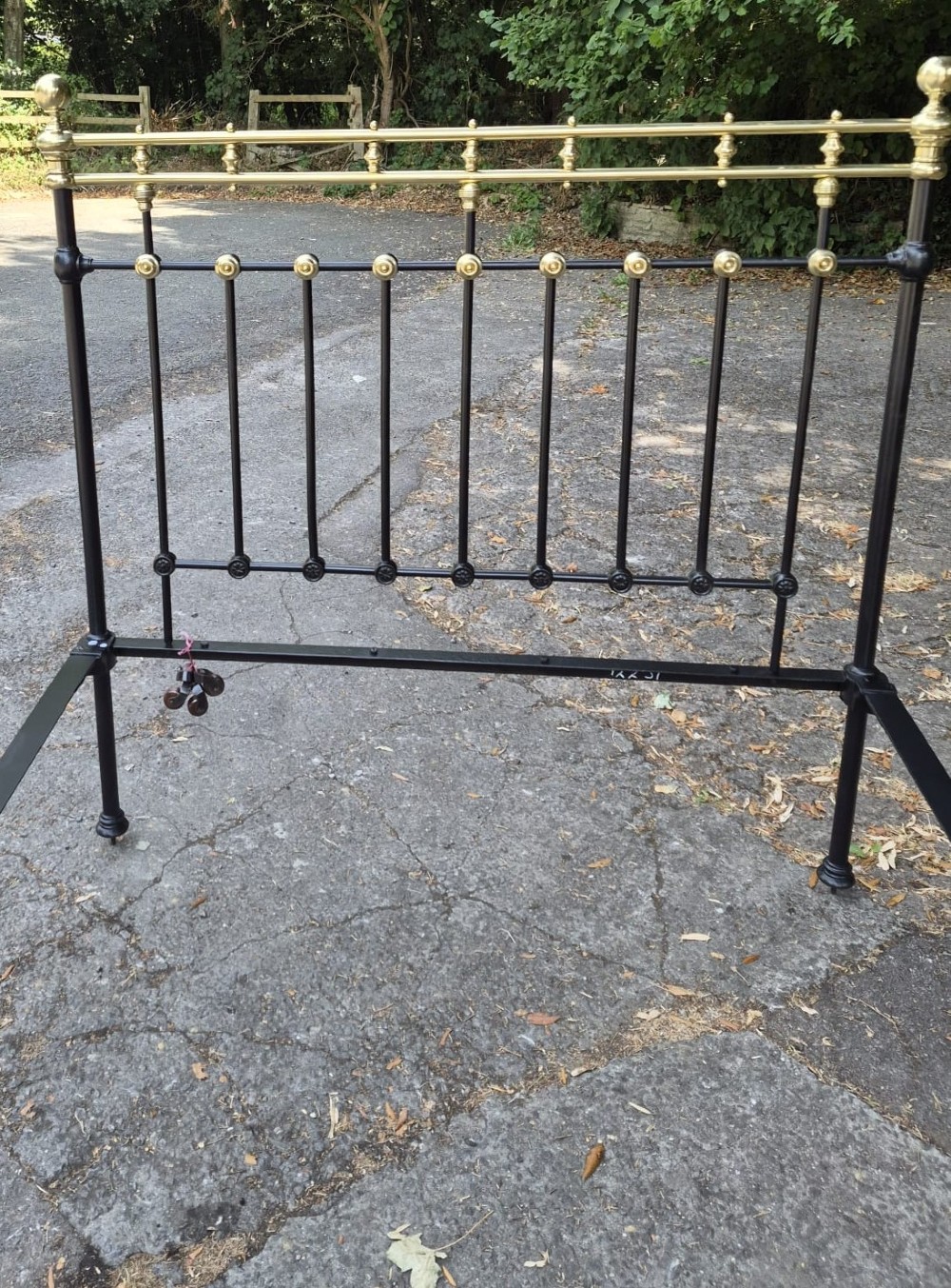 A Victorian double-size black iron bedstead featuring polished brass top rails, brass vertical mounts, and ball finials. View II