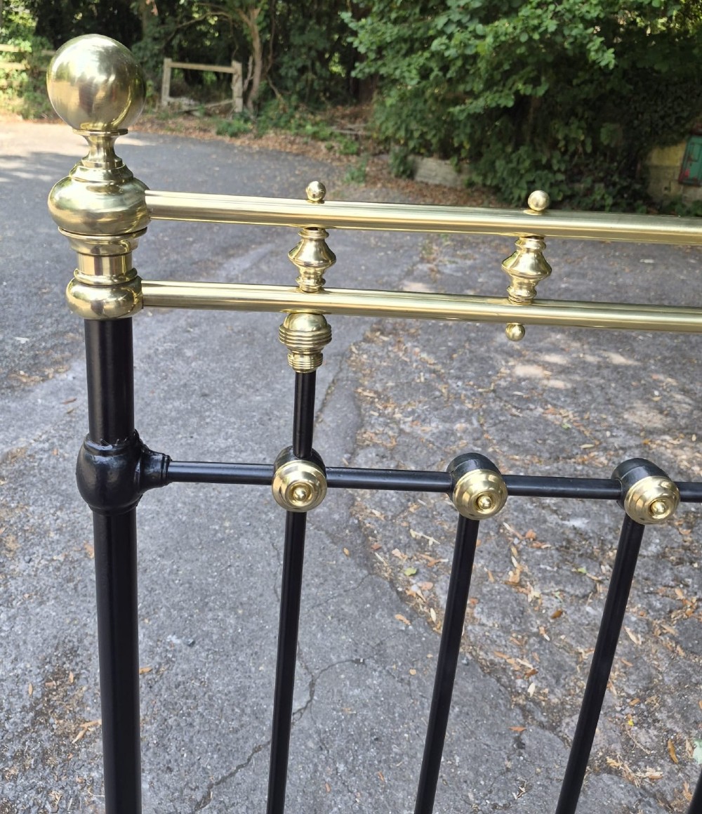 A Victorian double-size black iron bedstead featuring polished brass top rails, brass vertical mounts, and ball finials. View III
