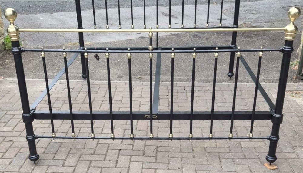 A Victorian super king size bedstead featuring a black painted cast iron frame with brass top rails, brass ball finials, and vertical spindles. View III