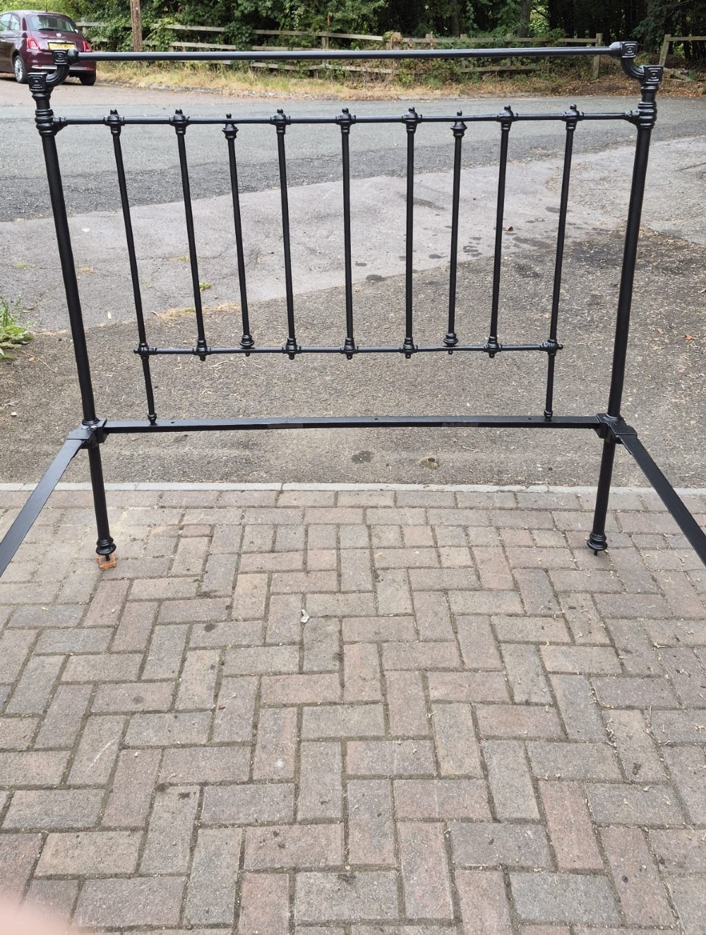 A black painted Victorian iron bed frame featuring vertical spindles, ornate cast joints, and matching headboard and footboard. View II