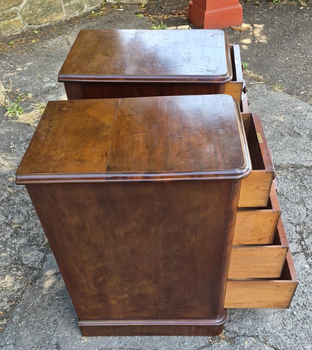 A pair of Victorian mahogany bedside chests featuring four drawers each with turned wooden knobs and a solid plinth base. View IV