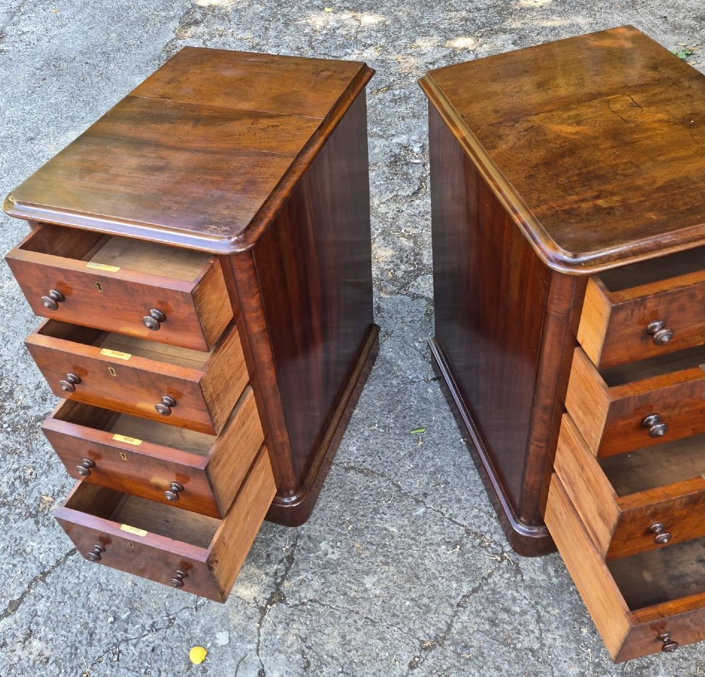 A pair of Victorian mahogany bedside chests featuring four drawers each with turned wooden knobs and a solid plinth base. View V