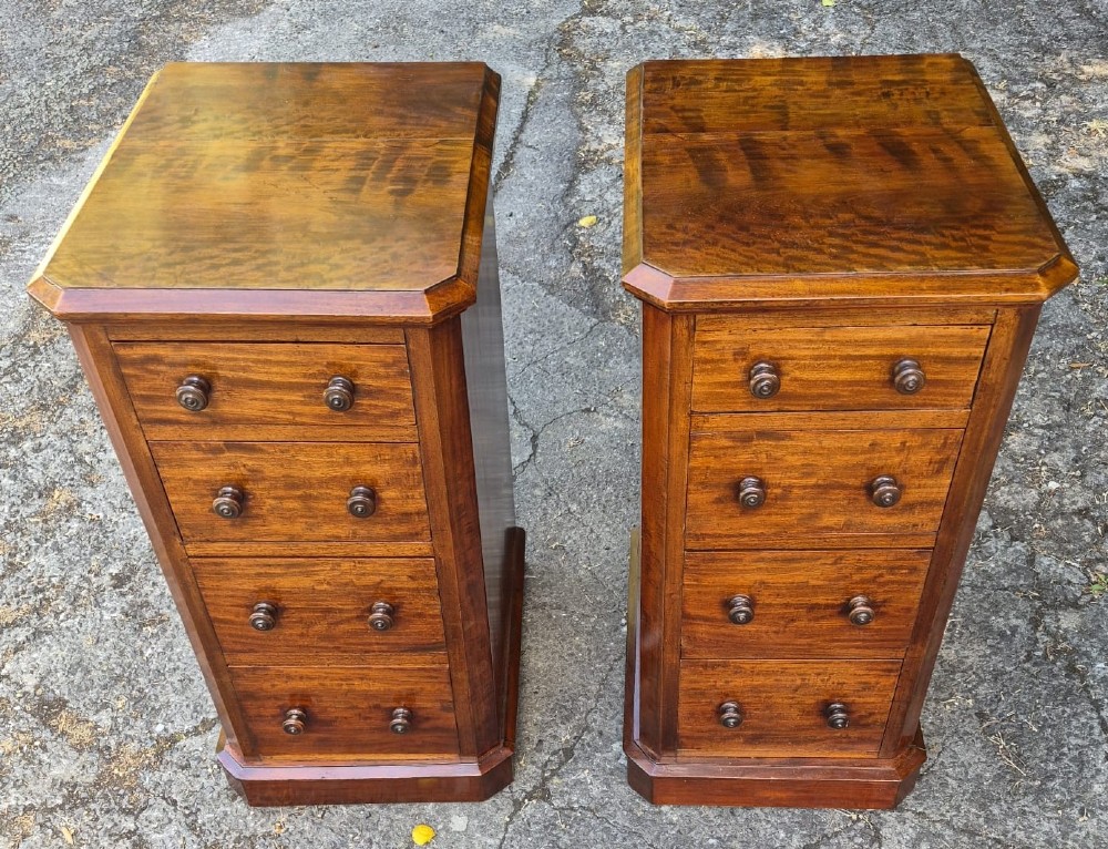 A pair of matching tall Victorian mahogany bedside chests featuring four drawers with turned wooden knobs and chamfered corners.