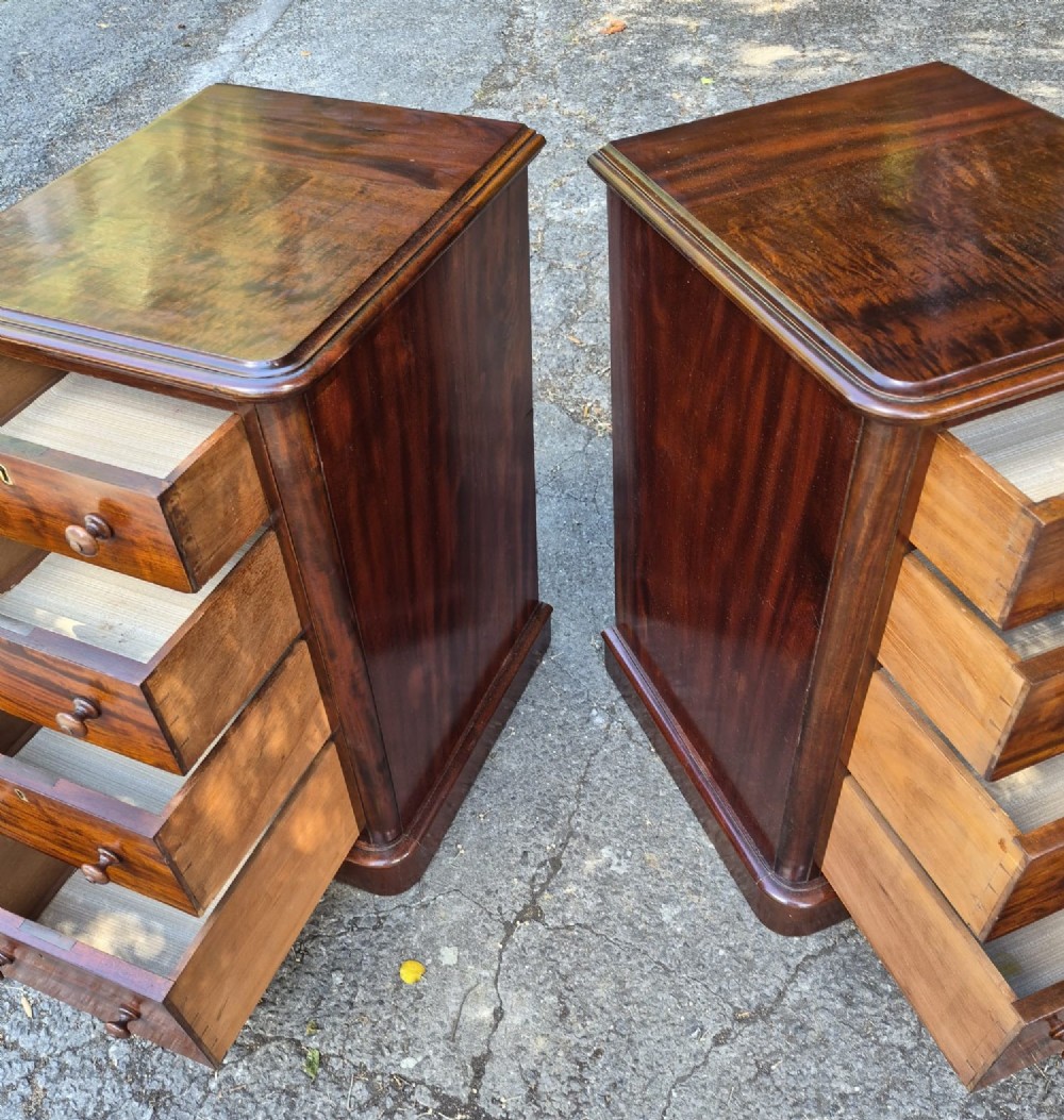 A matching pair of narrow Victorian mahogany bedside chests featuring four drawers each with turned wooden knobs and brass escutcheons on a solid plinth base. View VI