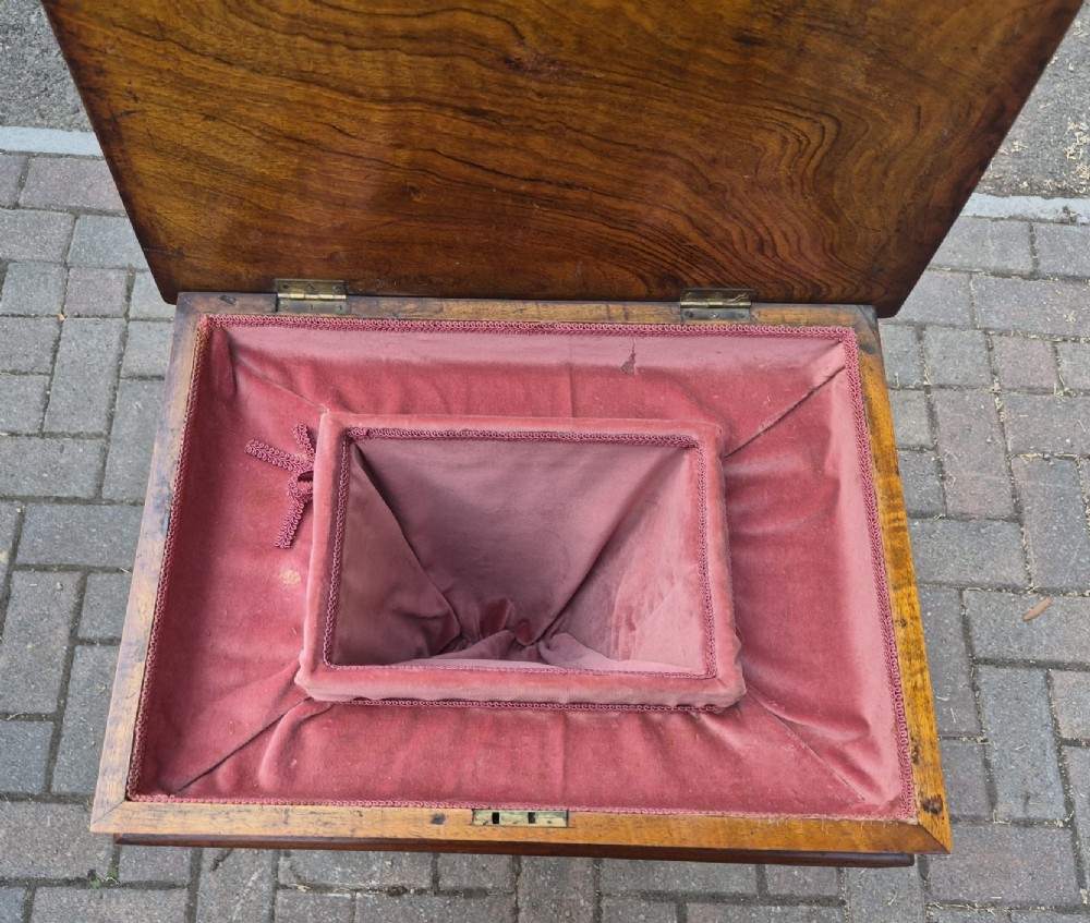 A Victorian burr walnut sewing table featuring a rectangular hinged top, a tapering fretwork work well, and a carved pedestal base resting on four cabriole legs. View III