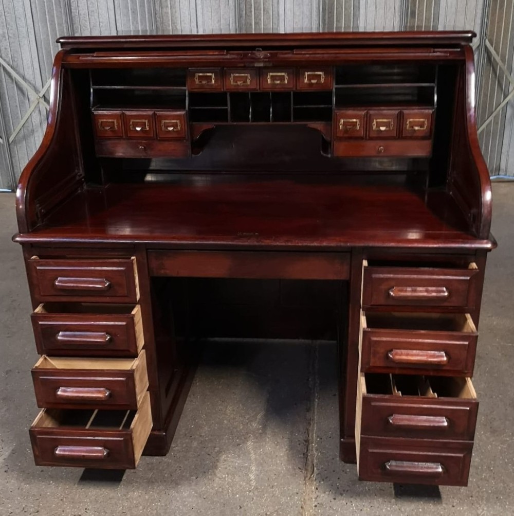 A Victorian mahogany roll top desk featuring twin pedestals, multiple drawers, and a closed slatted tambour cover. View III