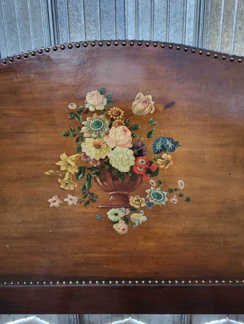 An Edwardian single bedstead upholstered in warm brown leather with hand-painted floral urn motifs, trimmed with brass studding and supported on carved cabriole legs. View III