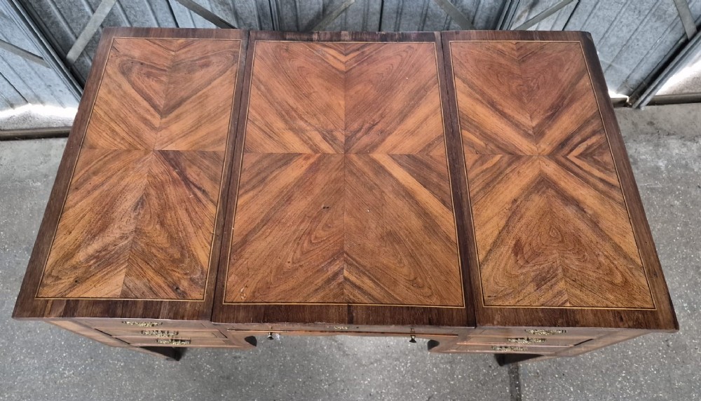 A 19th-century French inlaid kingwood and walnut poudreuse with a three-part geometric parquetry top, shaped kneehole apron, brass mounts, and tapered square legs. View II