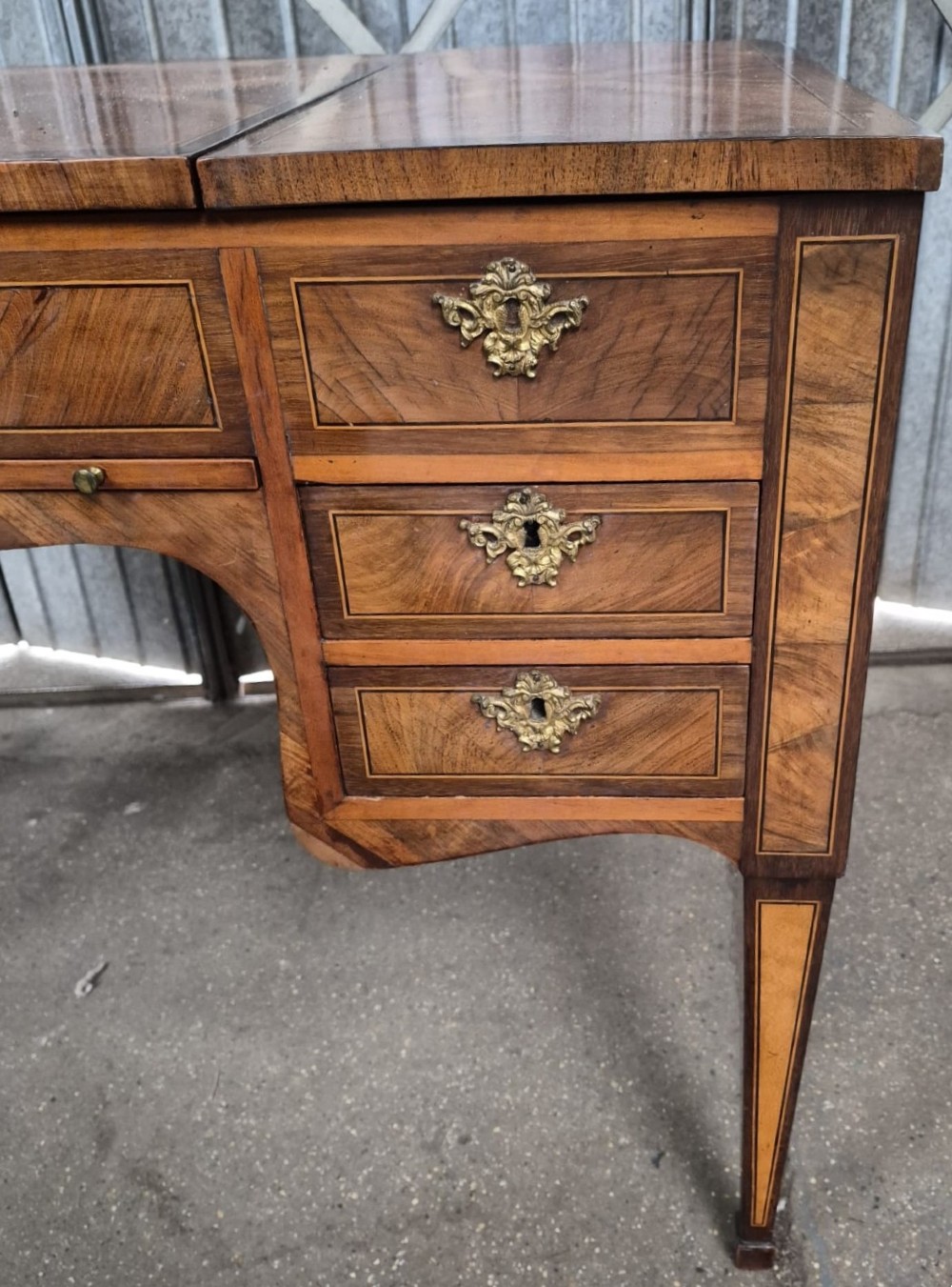 A 19th-century French inlaid kingwood and walnut poudreuse with a three-part geometric parquetry top, shaped kneehole apron, brass mounts, and tapered square legs. View V