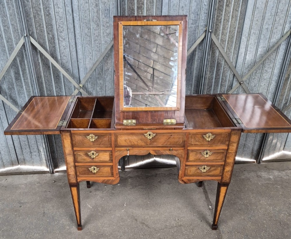 A 19th-century French inlaid kingwood and walnut poudreuse with a three-part geometric parquetry top, shaped kneehole apron, brass mounts, and tapered square legs. View VI