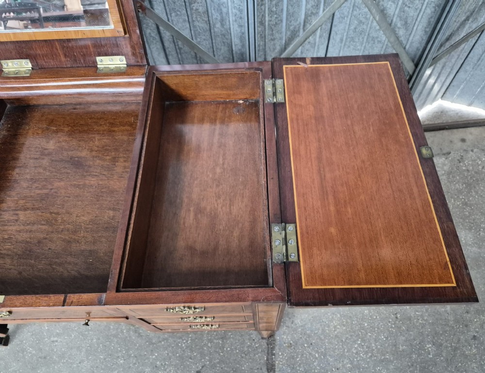A 19th-century French inlaid kingwood and walnut poudreuse with a three-part geometric parquetry top, shaped kneehole apron, brass mounts, and tapered square legs. View VII