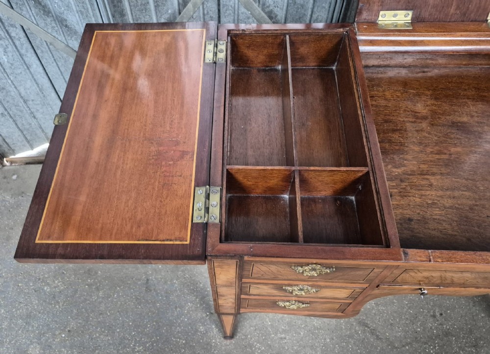 A 19th-century French inlaid kingwood and walnut poudreuse with a three-part geometric parquetry top, shaped kneehole apron, brass mounts, and tapered square legs. View VIII