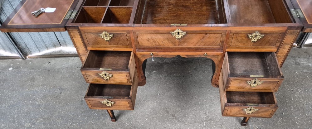 A 19th-century French inlaid kingwood and walnut poudreuse with a three-part geometric parquetry top, shaped kneehole apron, brass mounts, and tapered square legs. View X