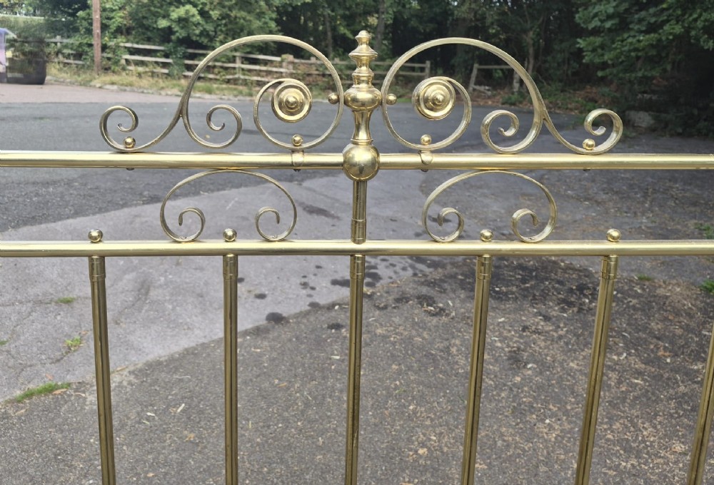 A Victorian brass half tester bedstead featuring an intricate scrolled headboard, turned corner posts, decorative finials, and an upper canopy frame. View II
