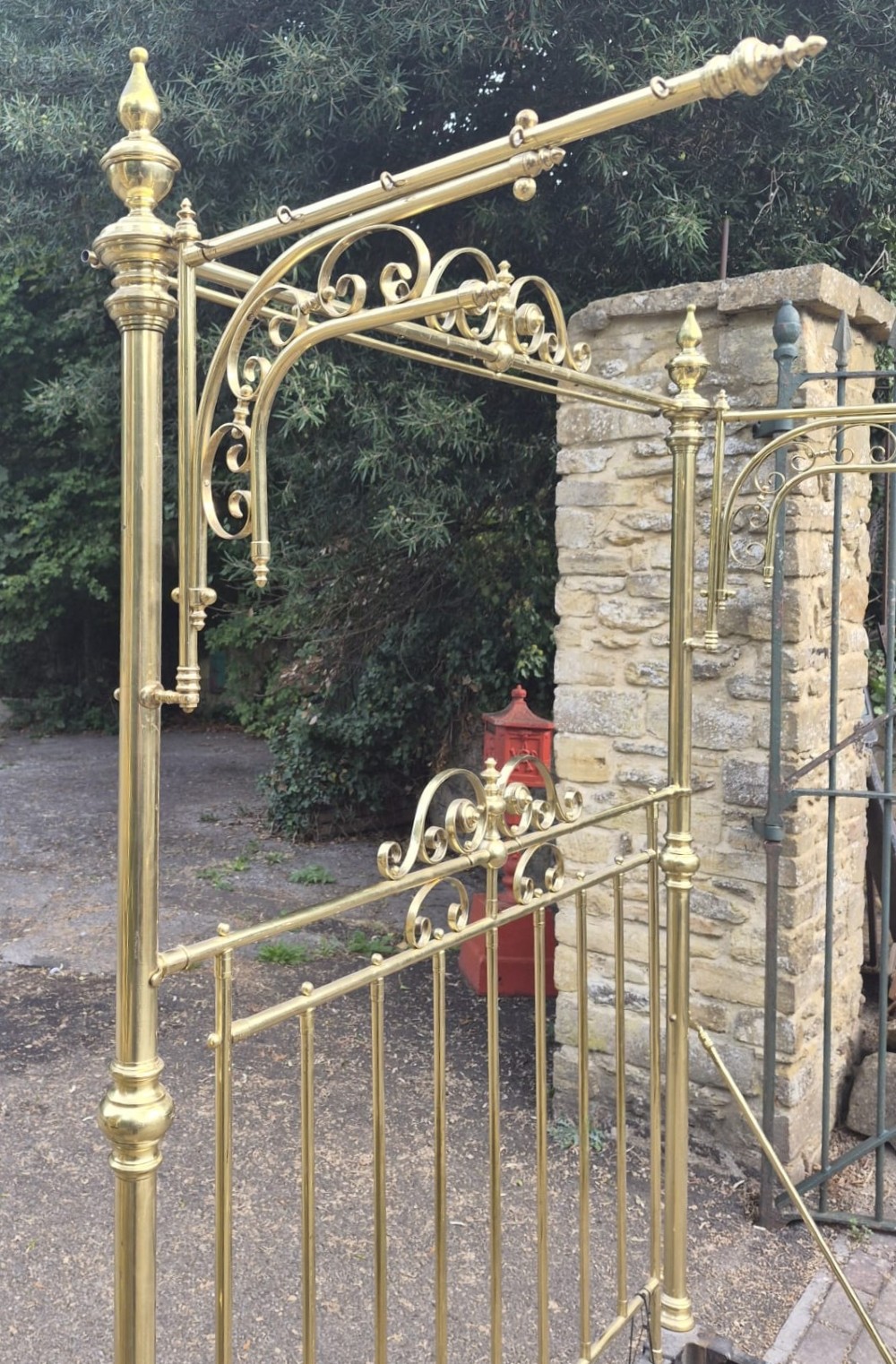 A Victorian brass half tester bedstead featuring an intricate scrolled headboard, turned corner posts, decorative finials, and an upper canopy frame. View IV