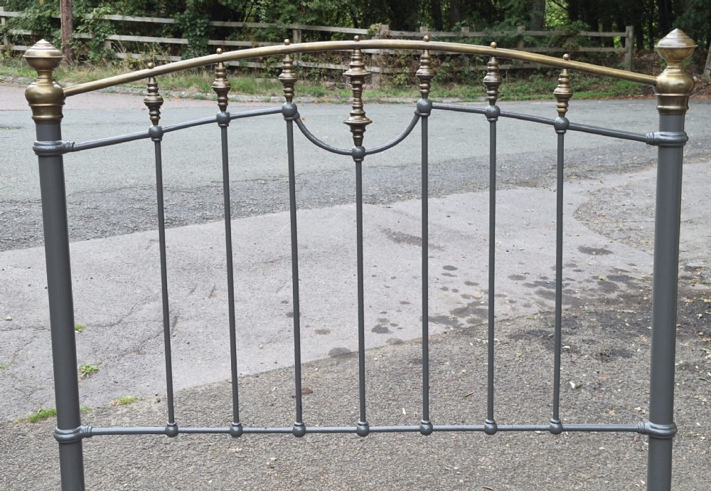 A Victorian double bedstead featuring a dark grey painted iron frame with vertical spindles and a top rail adorned with brass finials. View III