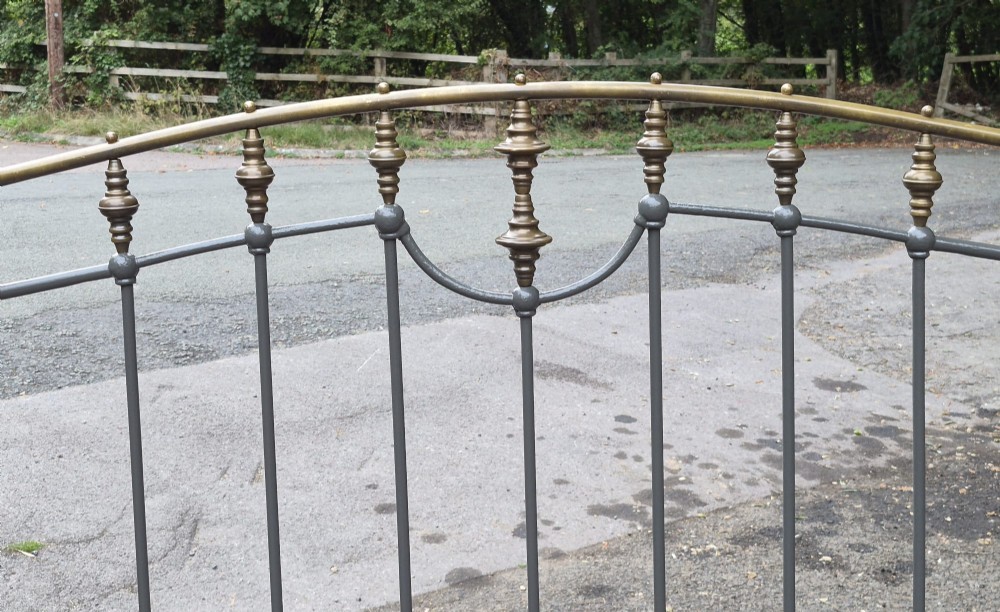 A Victorian double bedstead featuring a dark grey painted iron frame with vertical spindles and a top rail adorned with brass finials. View IV