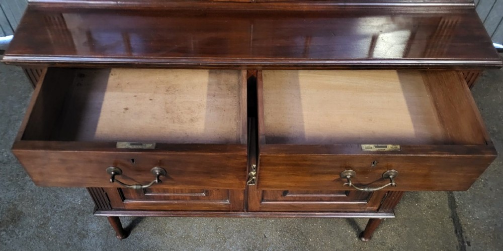 An Edwardian mahogany glazed bookcase cabinet featuring two upper glass doors with geometric glazing bars, two base drawers, and two panelled cupboard doors. View IV