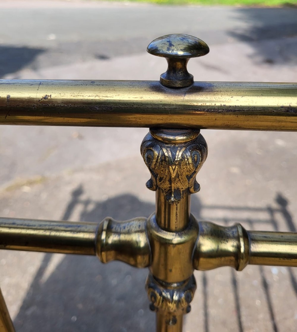 A Victorian small double brass bedstead featuring vertical brass spindles, decorative finials, green painted iron side rails, and white ceramic castors. View III
