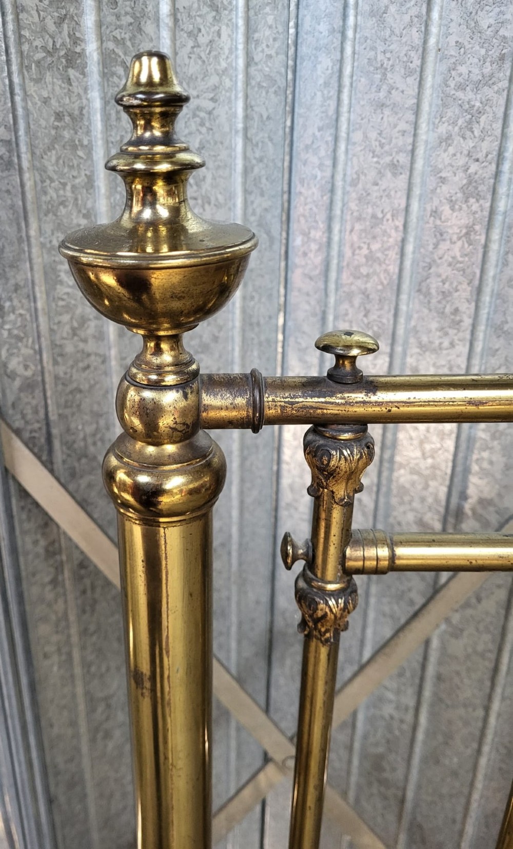 A Victorian brass small double bedstead featuring vertical spindles, decorative brass finials, side rails, and ceramic castors. View III