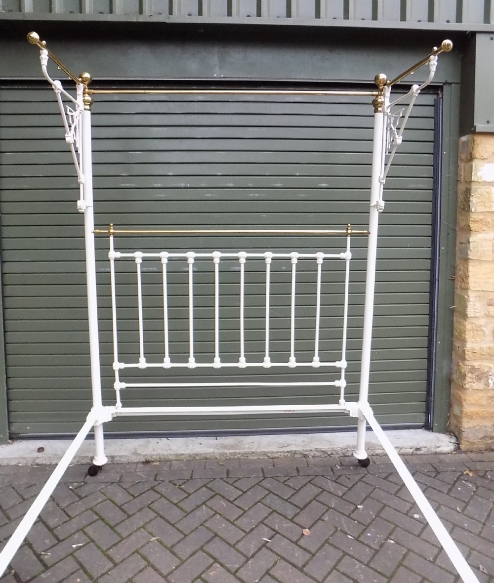 A Victorian brass and painted iron king size half tester bedstead featuring turned brass spindles, decorative finials, and an overhead frame. View III