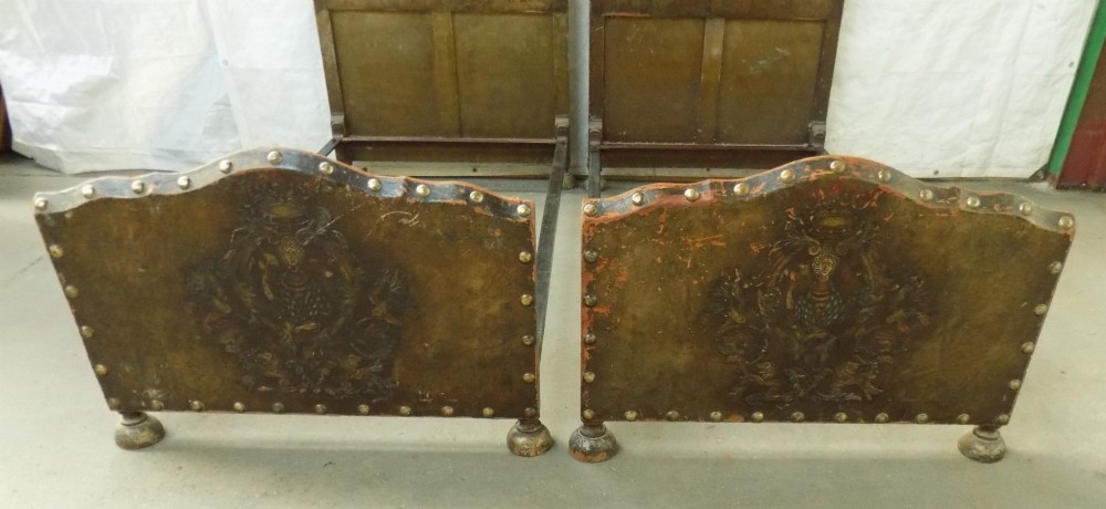 A pair of matching single bedsteads upholstered in aged brown hand-painted leather with brass stud trimming and arched tops. View III
