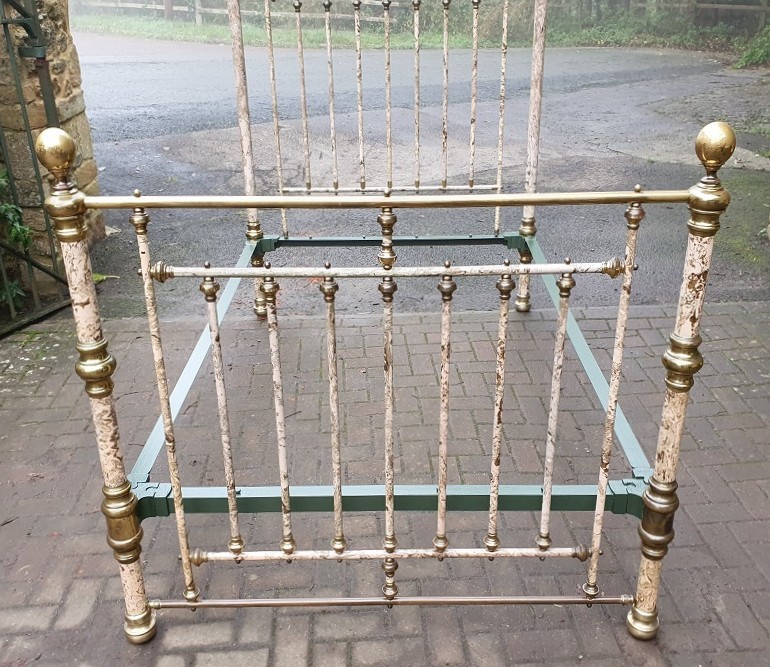 A Victorian brass and painted iron bedstead featuring turned vertical spindles, brass top rails, and spherical brass finials.