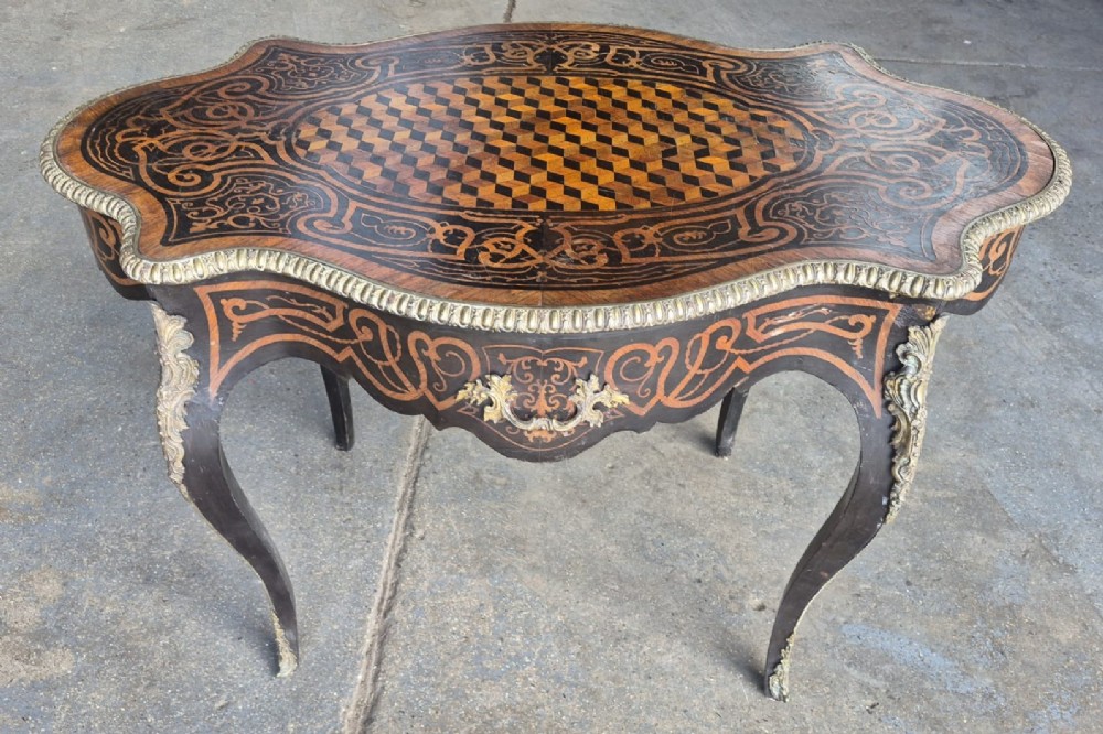 A 19th-century French kingwood centre table featuring a shaped serpentine top with geometric parquetry inlay, scroll marquetry borders, ormolu mounts, and cabriole legs.