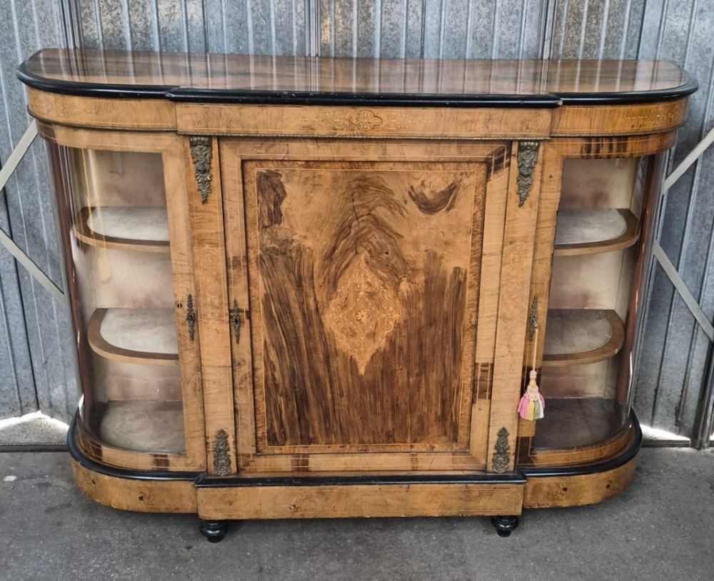 A Victorian burr walnut credenza featuring a central door with inlaid marquetry, ebonised top and base mouldings, metal mounts, and two curved glass side compartments.