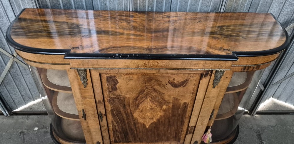 A Victorian burr walnut credenza featuring a central door with inlaid marquetry, ebonised top and base mouldings, metal mounts, and two curved glass side compartments. View II