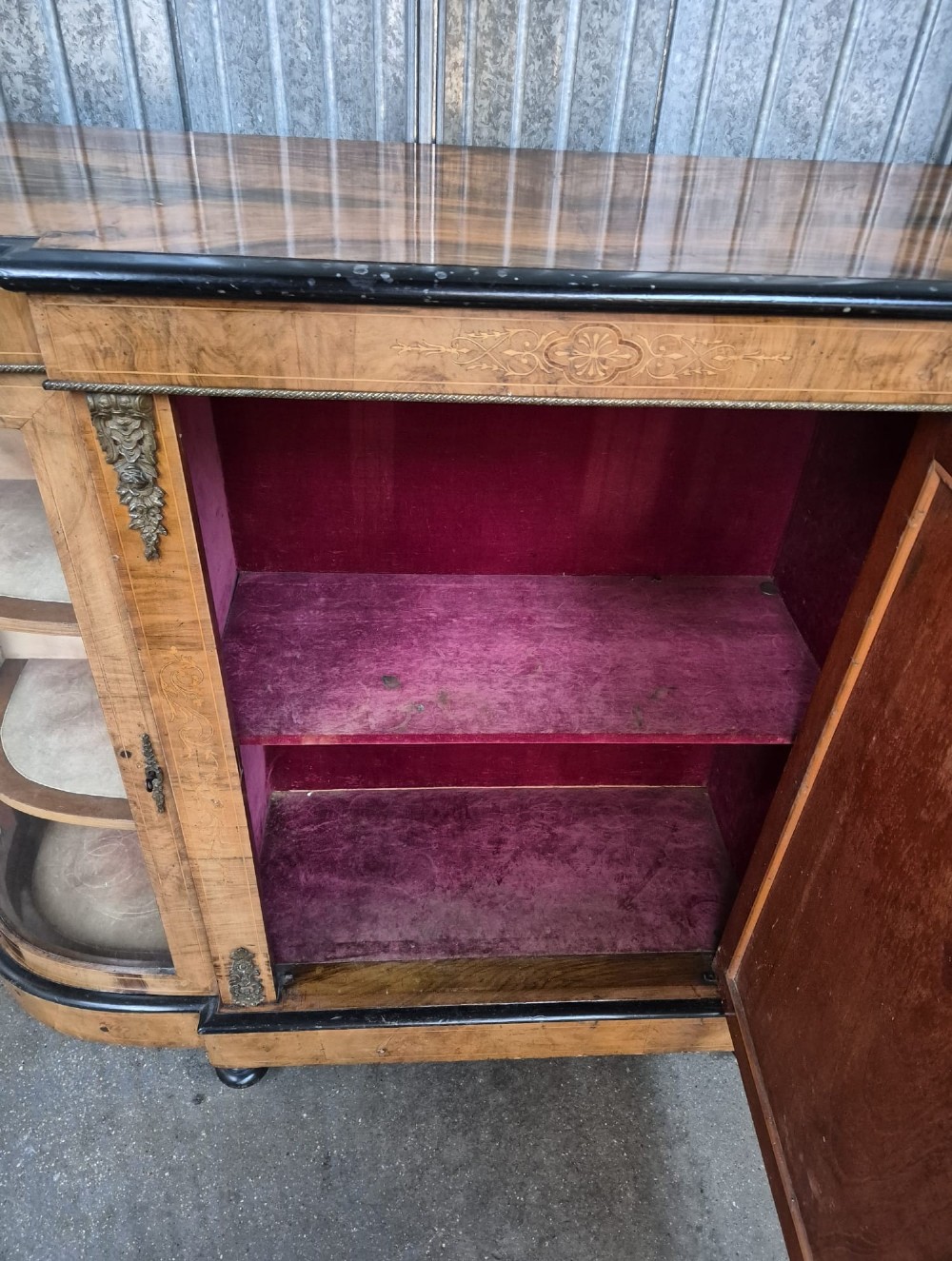 A Victorian burr walnut credenza featuring a central door with inlaid marquetry, ebonised top and base mouldings, metal mounts, and two curved glass side compartments. View IV