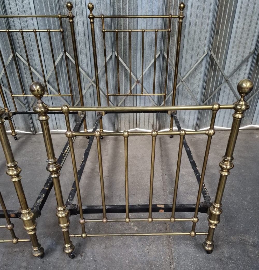 A pair of matching Victorian brass single bedsteads featuring vertical tubular spindles, ball finials, and castors. View III