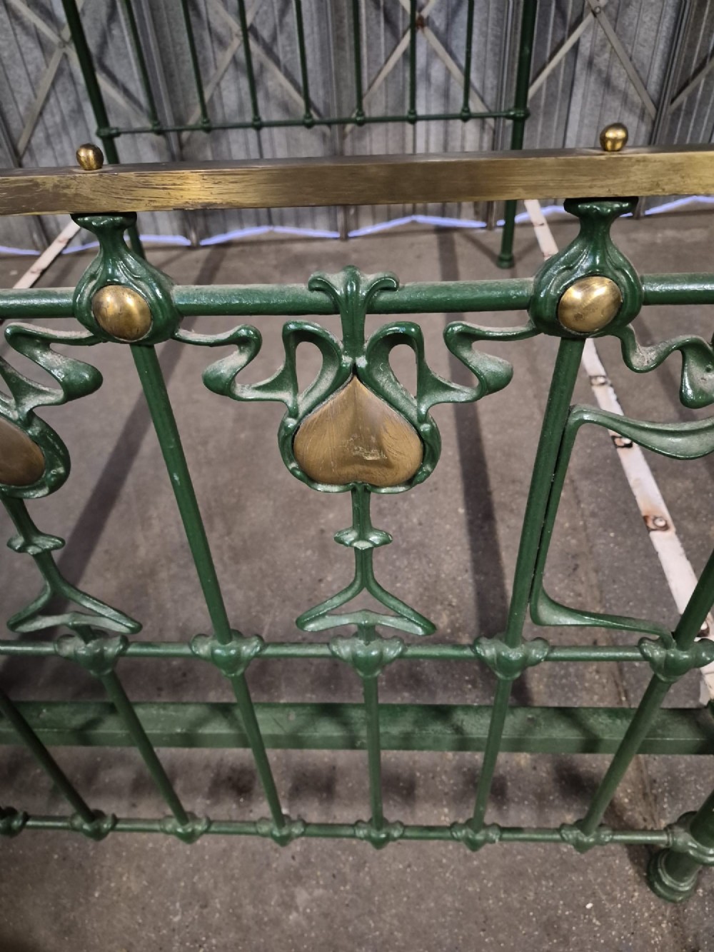 A Victorian Art Nouveau double bedstead featuring dark green painted iron frames, stylized heart-shaped motifs, and brass top rails with finials. View IV