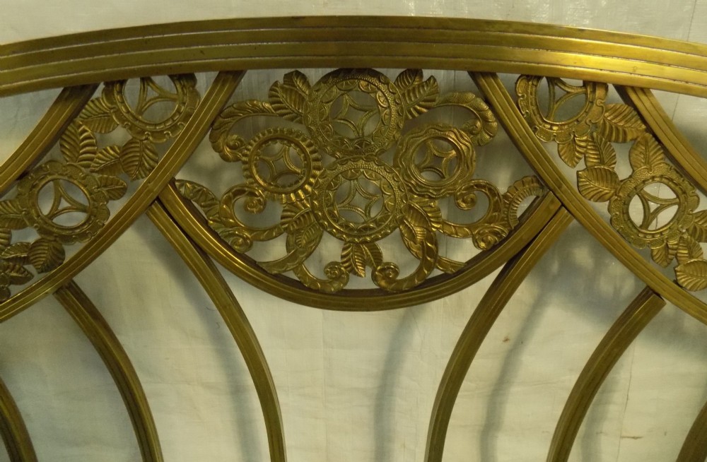 A late 19th-century brass bedstead with an arched headboard and footboard featuring detailed scrollwork and vertical spindles. View IV