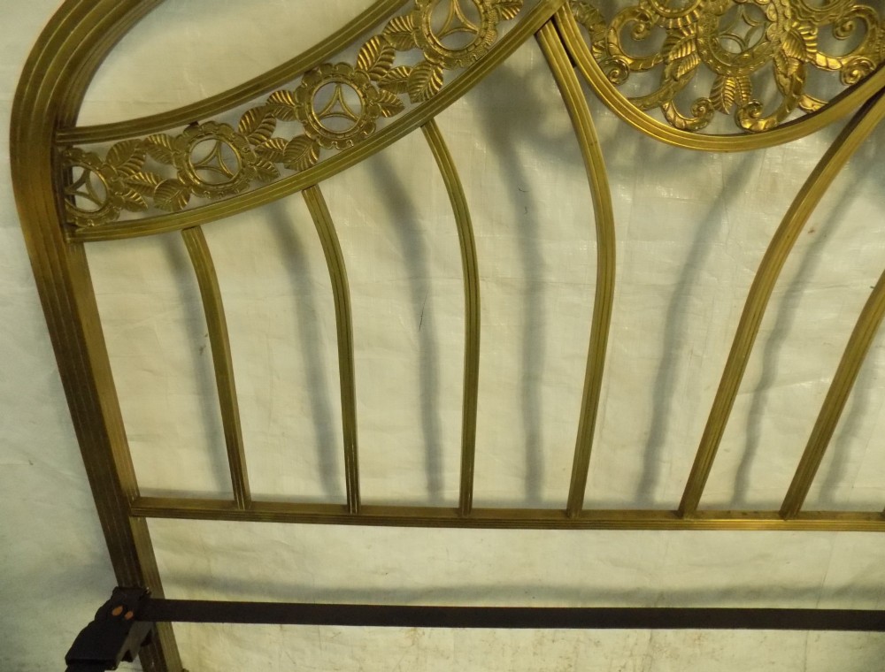A late 19th-century brass bedstead with an arched headboard and footboard featuring detailed scrollwork and vertical spindles. View VI
