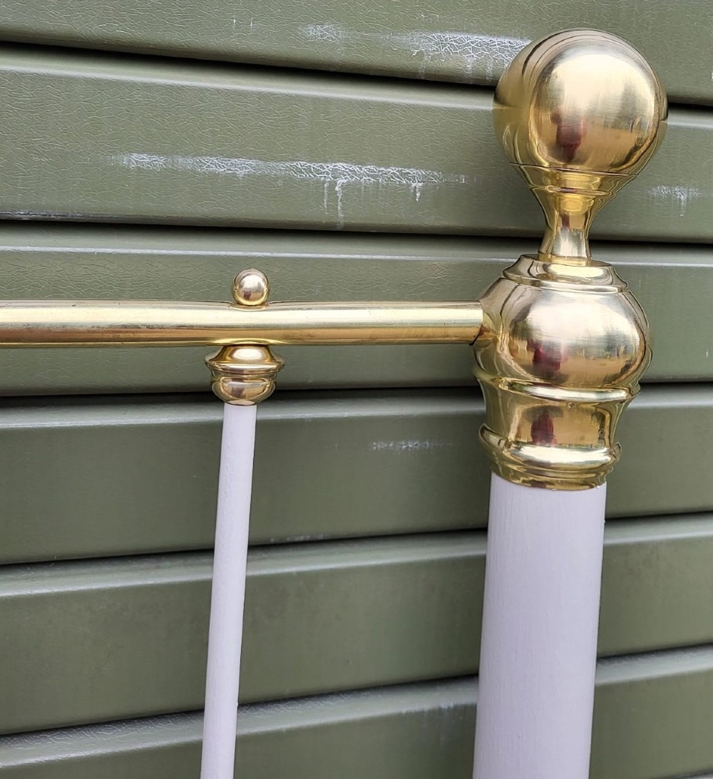A Victorian king-size metal headboard painted white with a decorative brass top rail, corner finials, and vertical spindles. View III