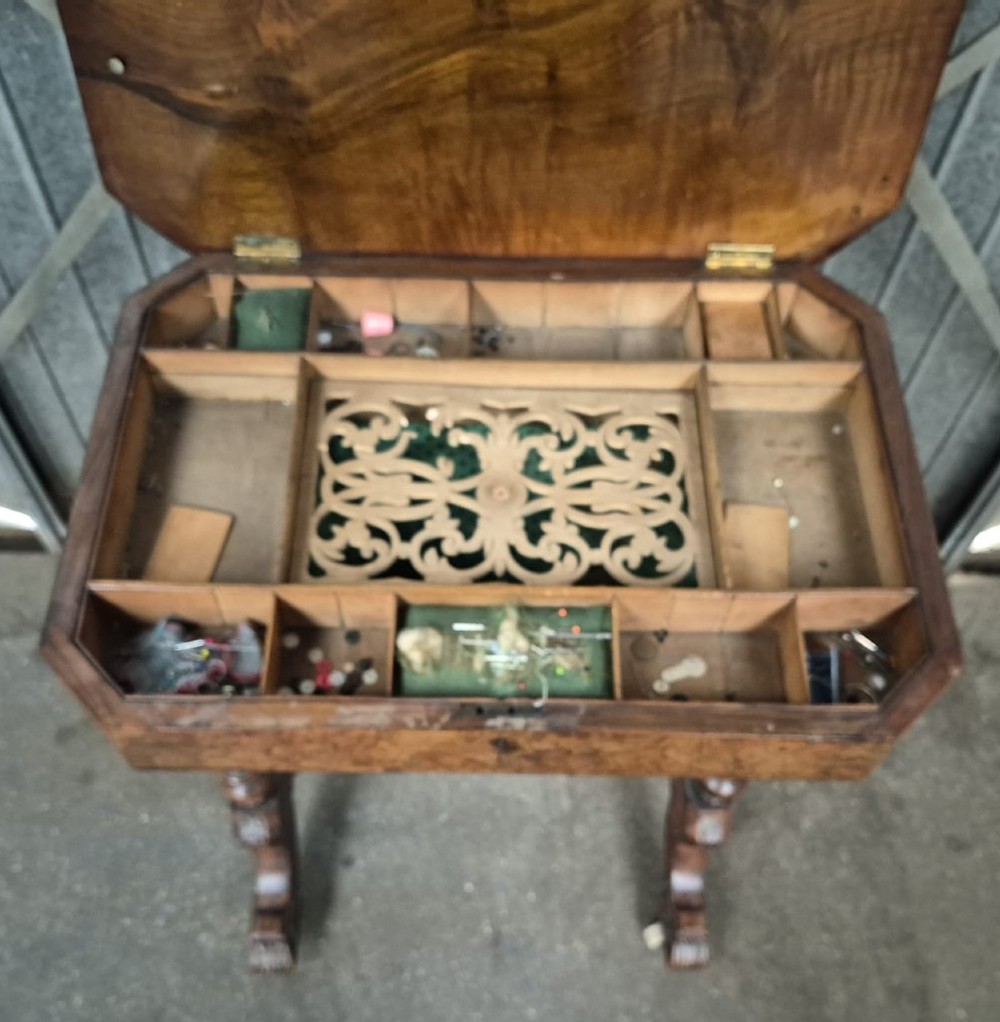 An antique Victorian burr walnut sewing table featuring ebonised banded inlay, a drop-down work basket, turned column legs, and a stretcher base with carved feet. View III