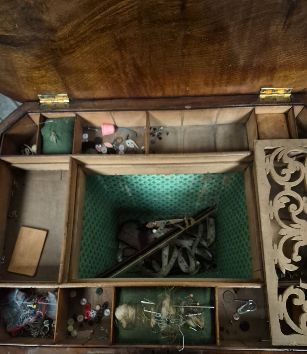 An antique Victorian burr walnut sewing table featuring ebonised banded inlay, a drop-down work basket, turned column legs, and a stretcher base with carved feet. View IV